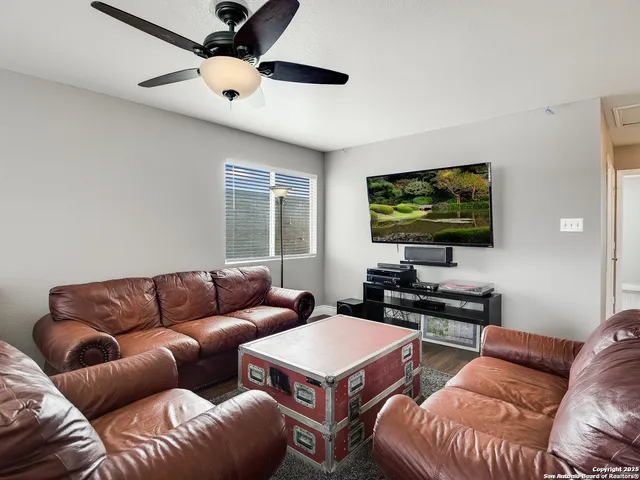 a living room with furniture a ceiling fan and a window