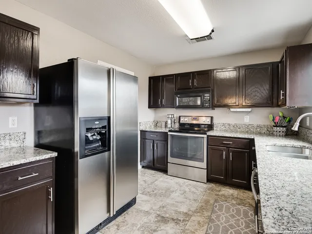 a kitchen with granite countertop a refrigerator and a stove top oven