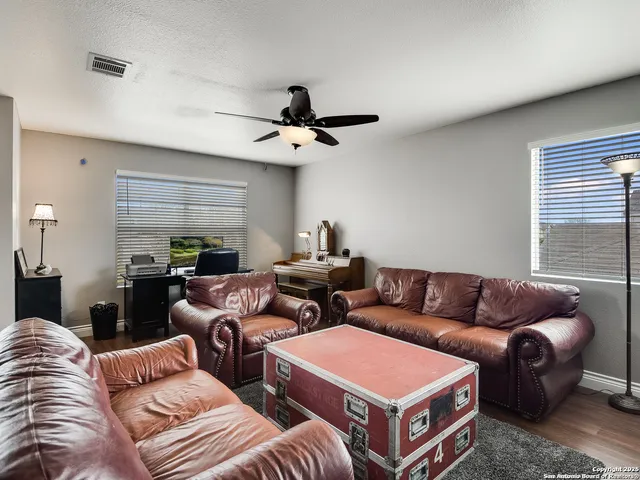 a living room with furniture a ceiling fan and a window