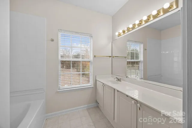 a bathroom with a granite countertop sink a large mirror and a bathtub