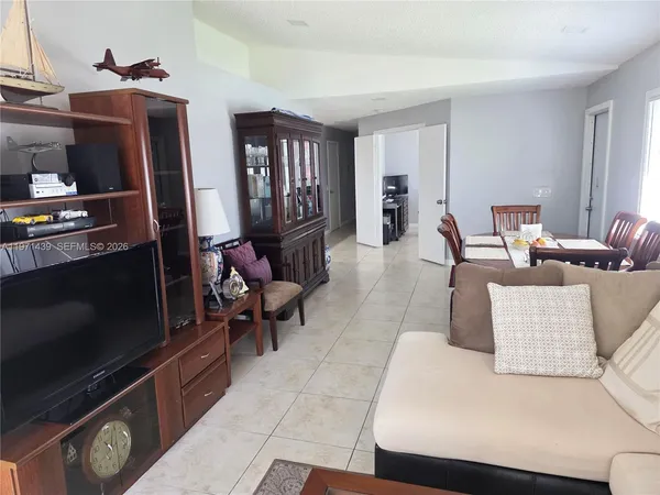 a living room with furniture a flat screen tv and a refrigerator