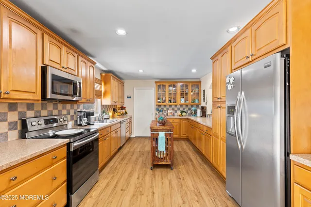 a kitchen with stainless steel appliances granite countertop a refrigerator a stove top oven a sink dishwasher and wooden cabinets with wooden floor