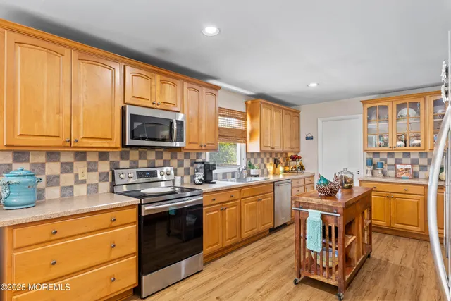 a kitchen with stainless steel appliances granite countertop a stove top oven a sink dishwasher a dining table and chairs with wooden floor