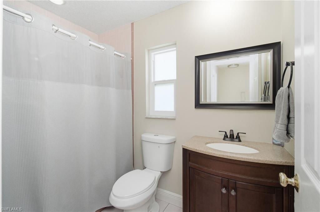 3022 47th Street Southwest Naples, FL 34116 - Photo 26 of 46 Bathroom featuring a dark wood vanity with a light-toned countertop, a framed mirror, and a window