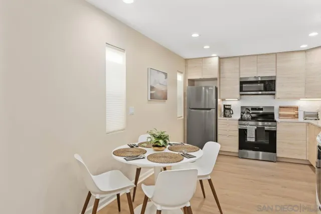 a kitchen with stainless steel appliances a refrigerator a stove a dining table and chairs