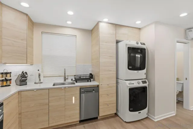 a kitchen with stainless steel appliances a sink a stove a washer dryer and white cabinets