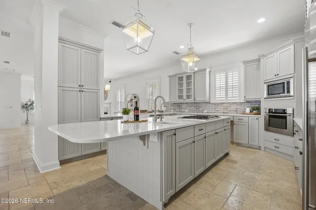 a large kitchen with kitchen island white cabinets and stainless steel appliances