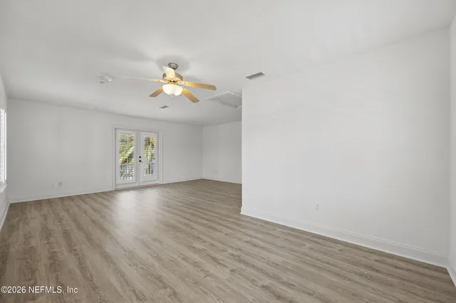 an empty room with wooden floor and windows