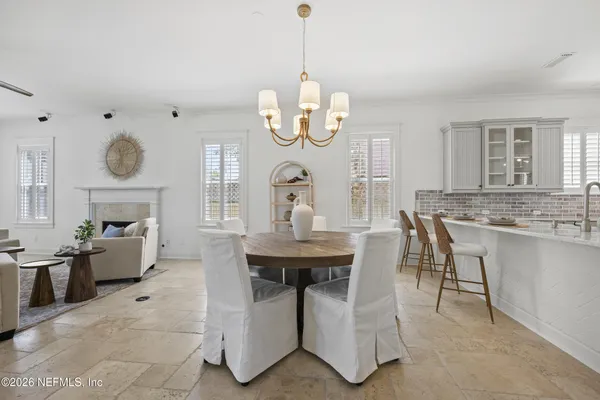 a dining room with wooden floor a chandelier a wooden table and chairs