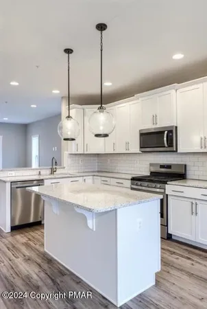 a kitchen with stainless steel appliances granite countertop a sink a stove a microwave a counter top space and cabinets