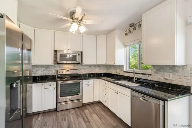 a kitchen with stainless steel appliances a sink dishwasher a stove and white cabinets