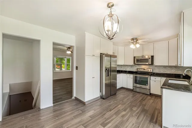 a kitchen with stainless steel appliances granite countertop a refrigerator a stove and a wooden floors