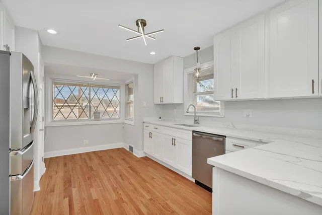 a large kitchen with kitchen island white cabinets and stainless steel appliances
