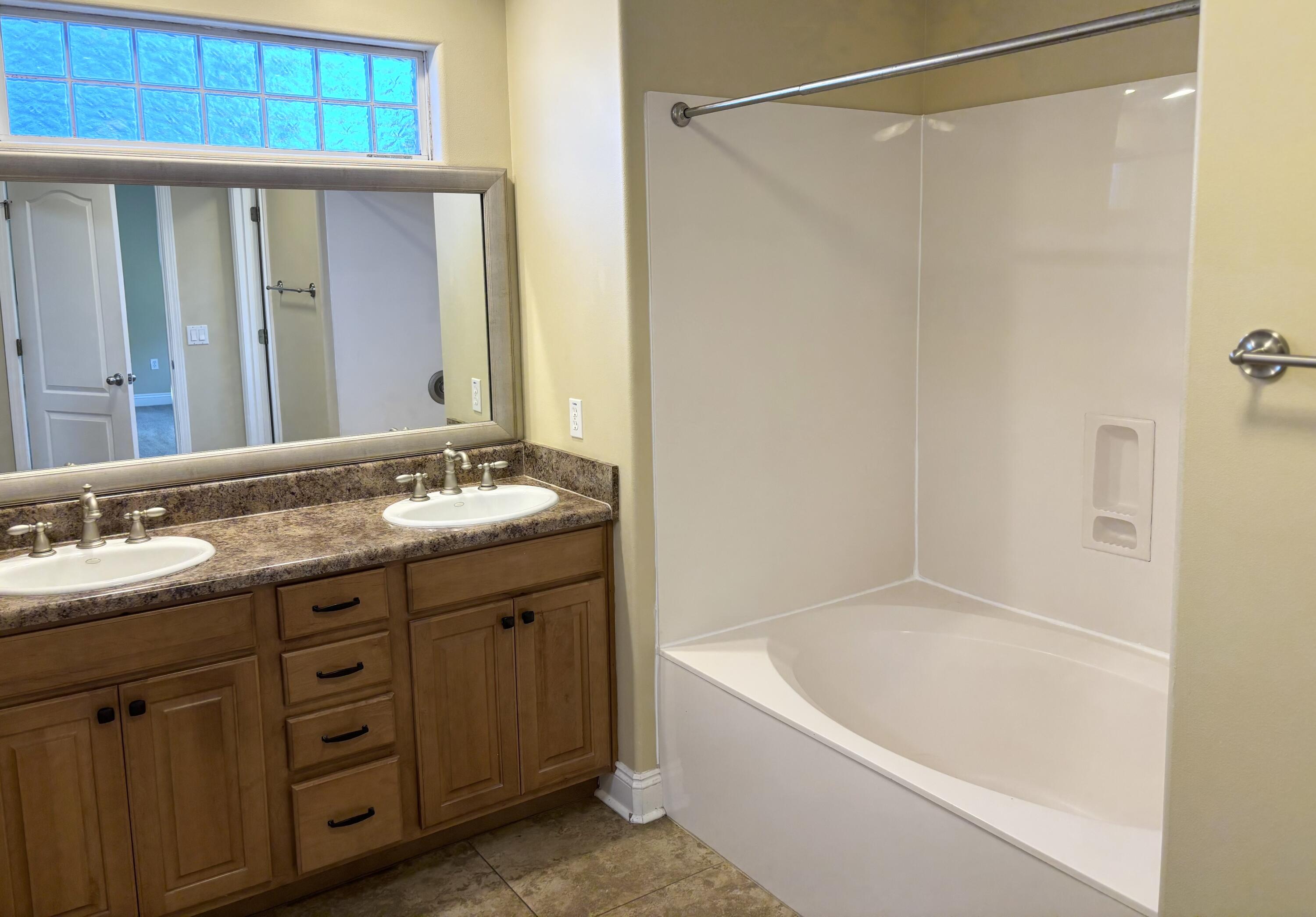 9561 Pouder Lane Navarre, FL 32566 - Photo 10 of 20 a bathroom with a granite countertop sink a mirror a shower and a bathtub