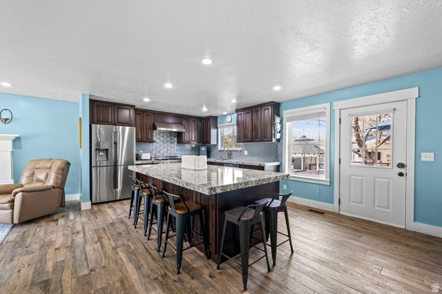 141 North 600 East Mapleton, UT 84664 - Photo 12 of 44 Kitchen featuring dark wood finish cabinetry, a kitchen breakfast bar, a center island, stainless steel refrigerator with ice dispenser, and a textured ceiling