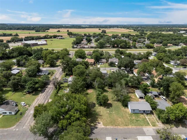 an aerial view of residential houses with outdoor space and trees