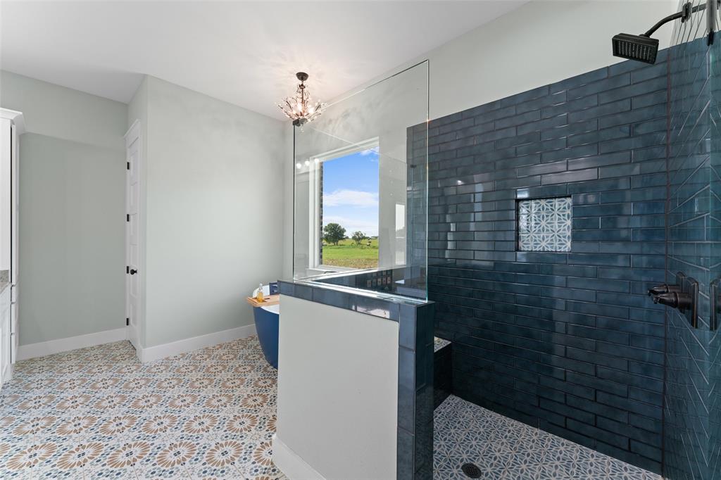 4411 Fm 751 Wills Point Wills Point, TX 75169 - Photo 24 of 40 Spacious bathroom featuring patterned floor tiling, a walk-in shower with dark blue subway tile, a built-in shower niche, and a freestanding soaking tub