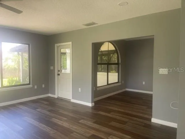 an empty room with wooden floor and windows
