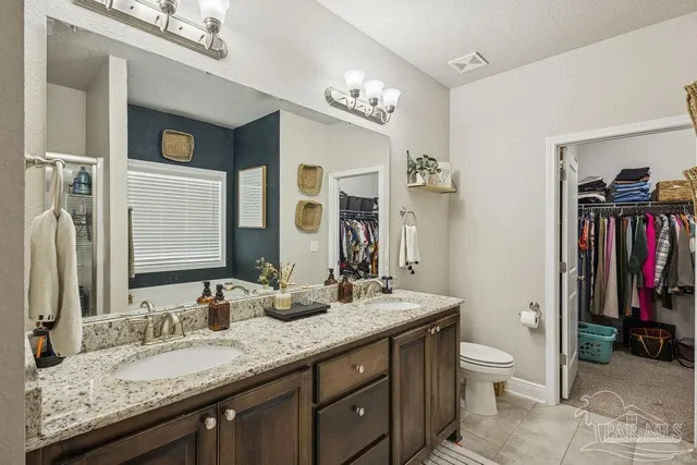 a bathroom with a granite countertop double vanity sink and a mirror