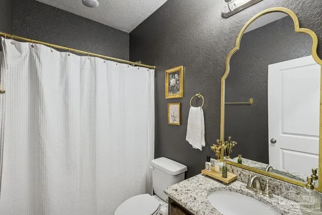 a bathroom with a granite countertop sink vanity mirror and toilet