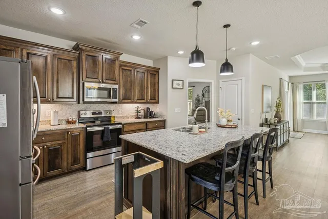 a kitchen with granite countertop a table chairs stainless steel appliances and wooden floor