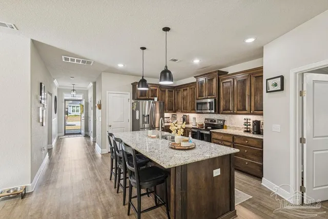a kitchen with a dining table cabinets appliances and wooden floor