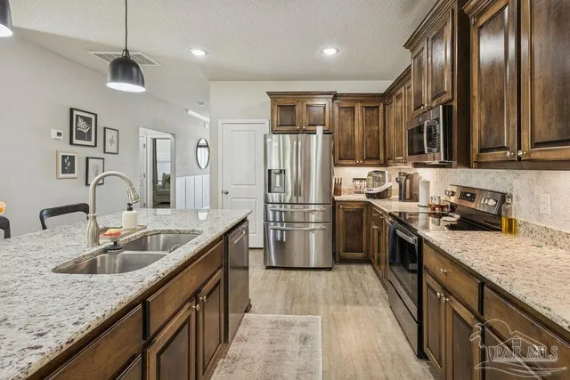 a kitchen with stainless steel appliances granite countertop a sink refrigerator and cabinets