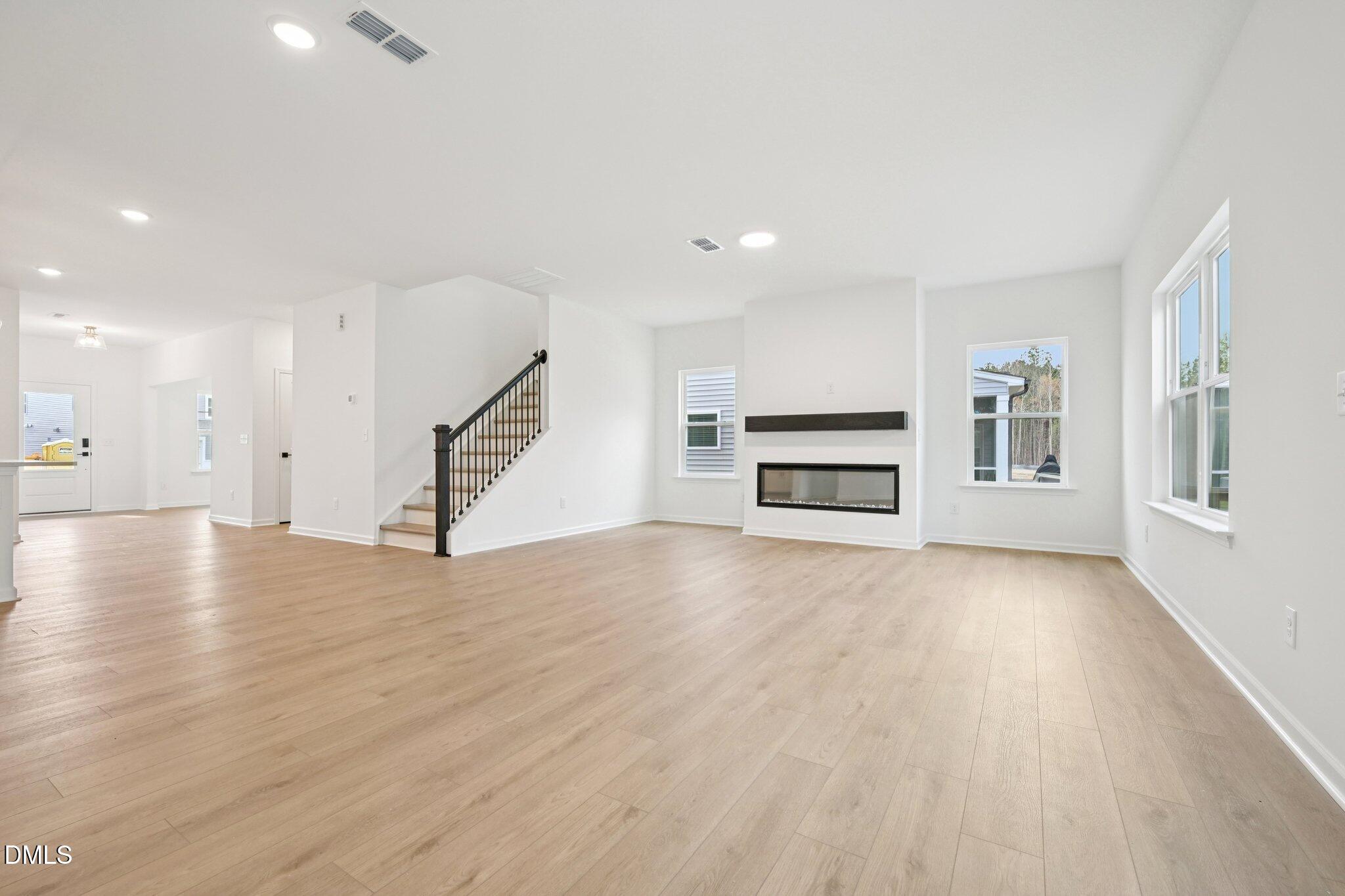 916 Fetching Place, Unit 344 Rolesville, NC 27571 - Photo 12 of 37 a view of an empty room with wooden floor windows and a kitchen view