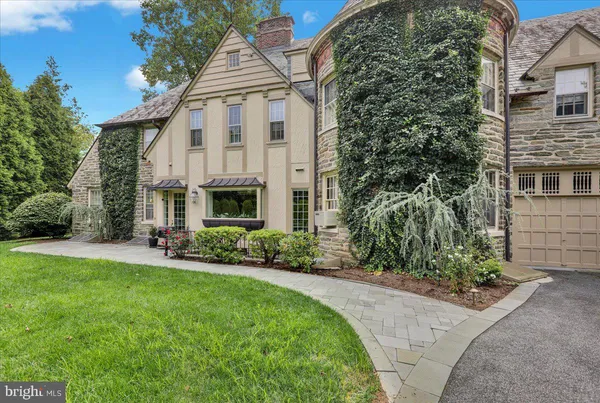 a view of a white house next to a yard with plants and trees