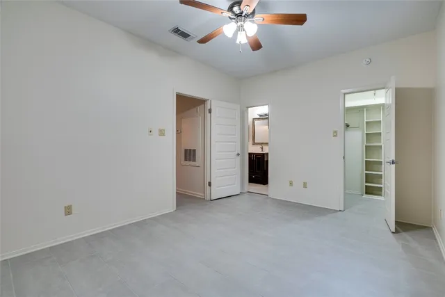 an empty room with closet and a ceiling fan