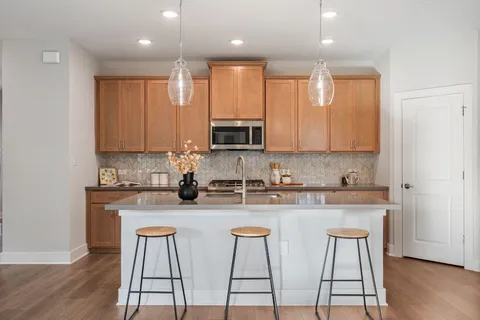 a kitchen with stainless steel appliances granite countertop a stove a sink a microwave a dining table and chairs with wooden floor