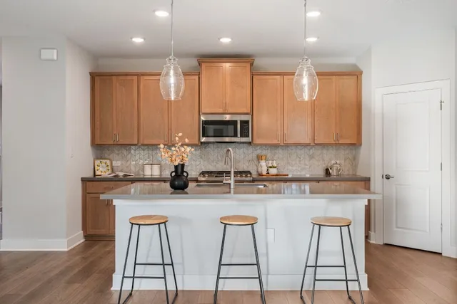 a kitchen with stainless steel appliances granite countertop a stove a sink a microwave a dining table and chairs with wooden floor