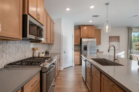 a kitchen with stainless steel appliances granite countertop a sink stove microwave and refrigerator