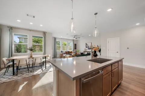 a kitchen with stainless steel appliances granite countertop a sink a stove and a wooden floors