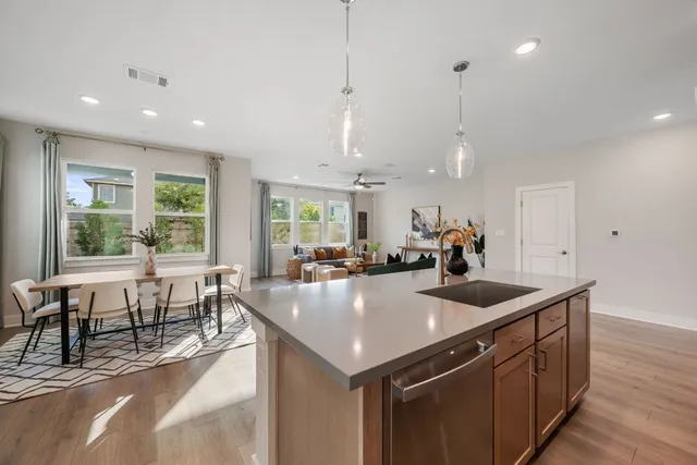 a kitchen with stainless steel appliances granite countertop a sink a stove and a wooden floors