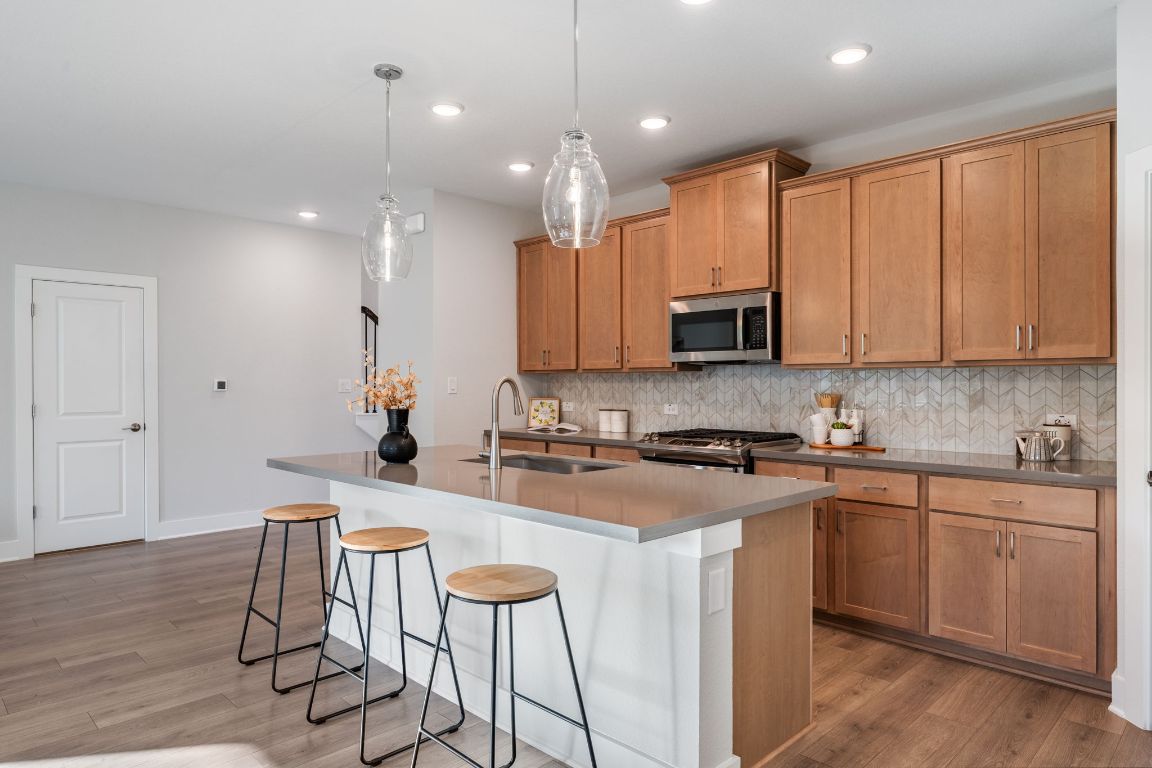 1403 Iberville Drive Pflugerville, TX 78660 - Photo 15 of 40 a kitchen with kitchen island granite countertop wooden cabinets and a refrigerator