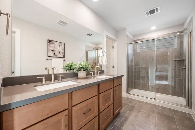 a bathroom with a double vanity sink mirror and shower