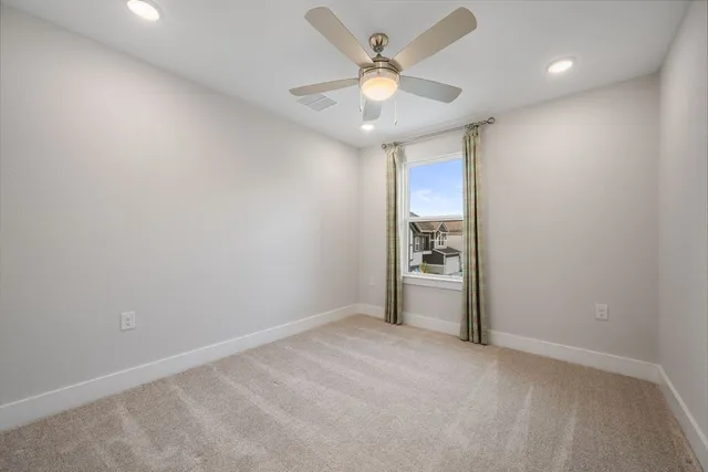 an empty room with a chandelier fan and windows