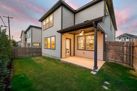 a view of backyard with wooden fence and large windows
