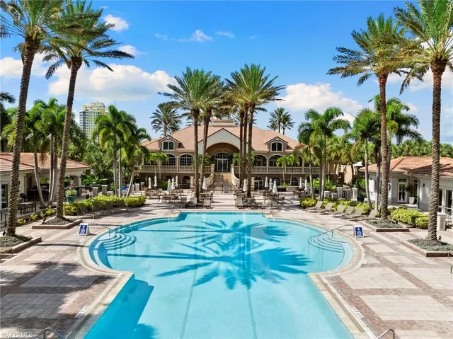 a view of a swimming pool with tables and chair and palm trees