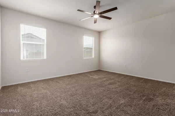an empty room with windows and fan