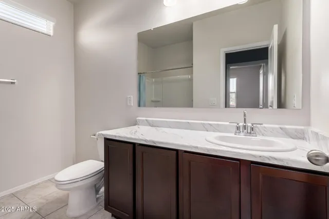 a bathroom with a granite countertop sink a toilet and a mirror