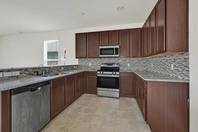 a kitchen with stainless steel appliances granite countertop a sink stove microwave and cabinets