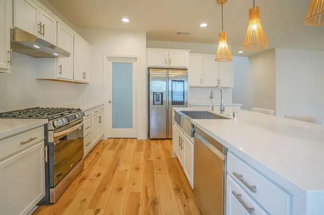 a kitchen with a sink a counter top space stainless steel appliances and cabinets