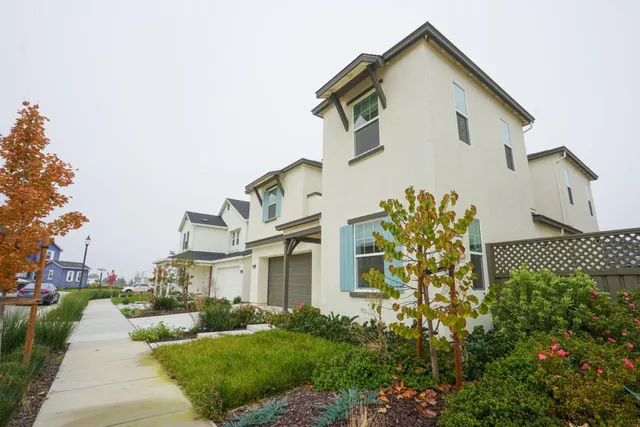 a view of a white house with a big yard and potted plants
