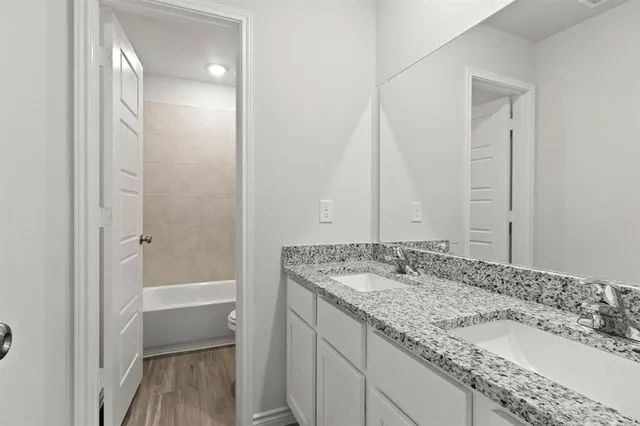 a bathroom with a granite countertop sink and a mirror a bathtub