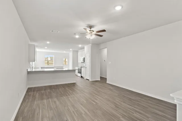 a view of a kitchen with wooden floor and a ceiling fan