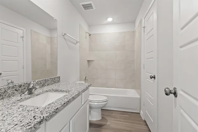 a bathroom with a granite countertop sink a toilet and shower