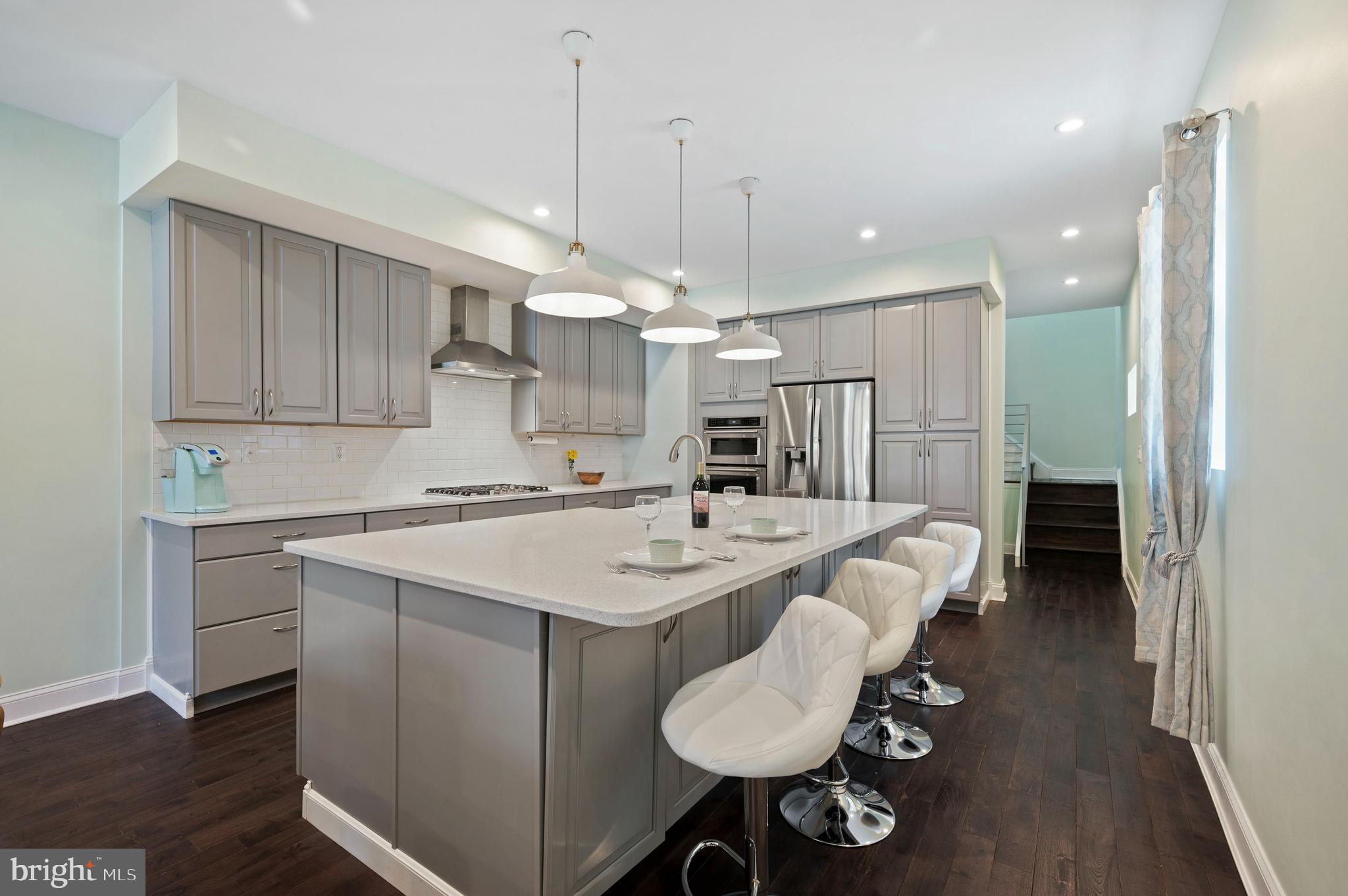 a kitchen with a sink a center island stainless steel appliances and cabinets