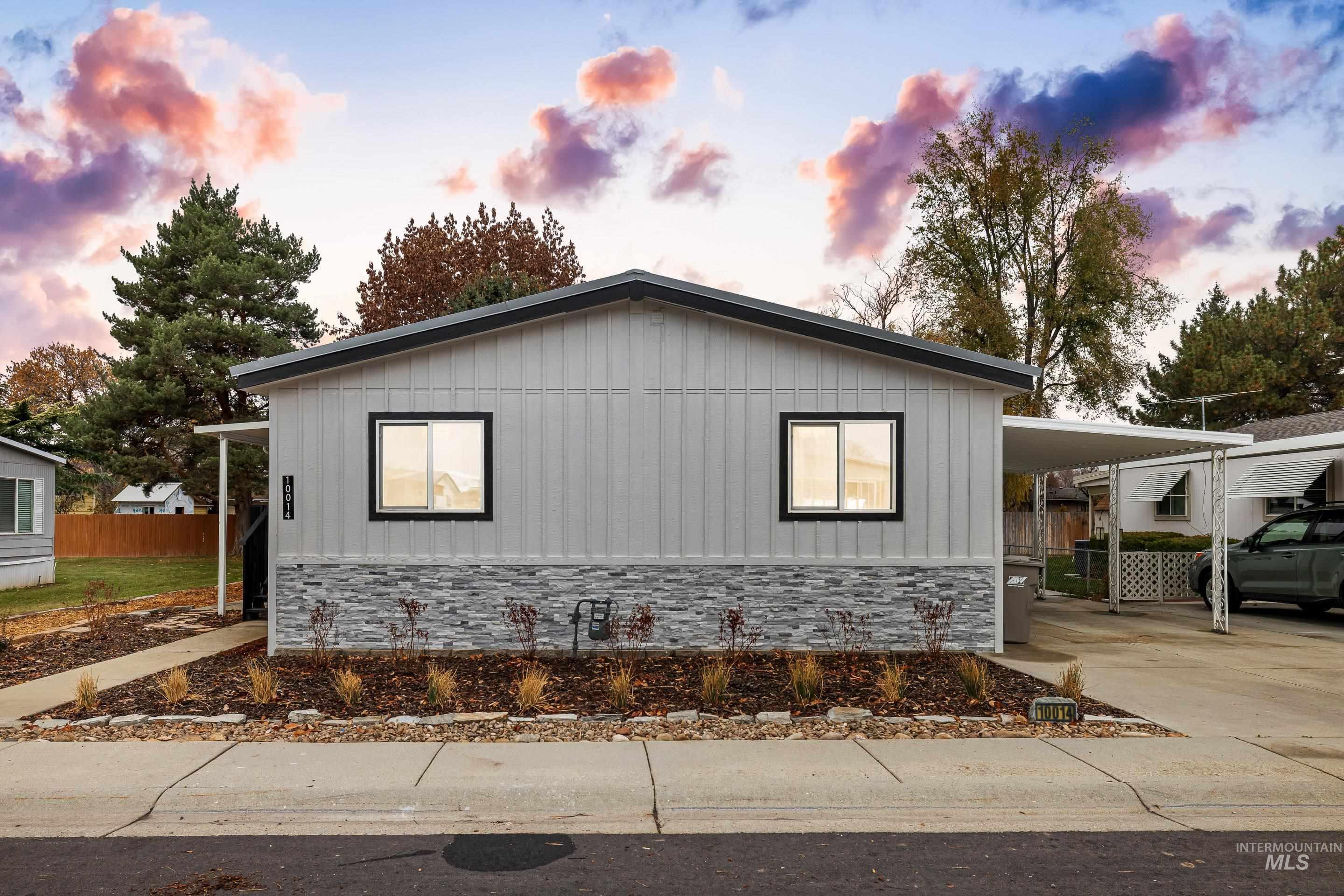 View of side of property with concrete driveway, stone siding, board and batten siding, and a carport